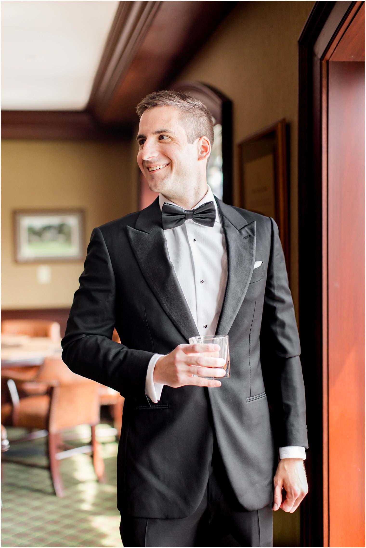 groom holds drink and looks over shoulder in New Jersey
