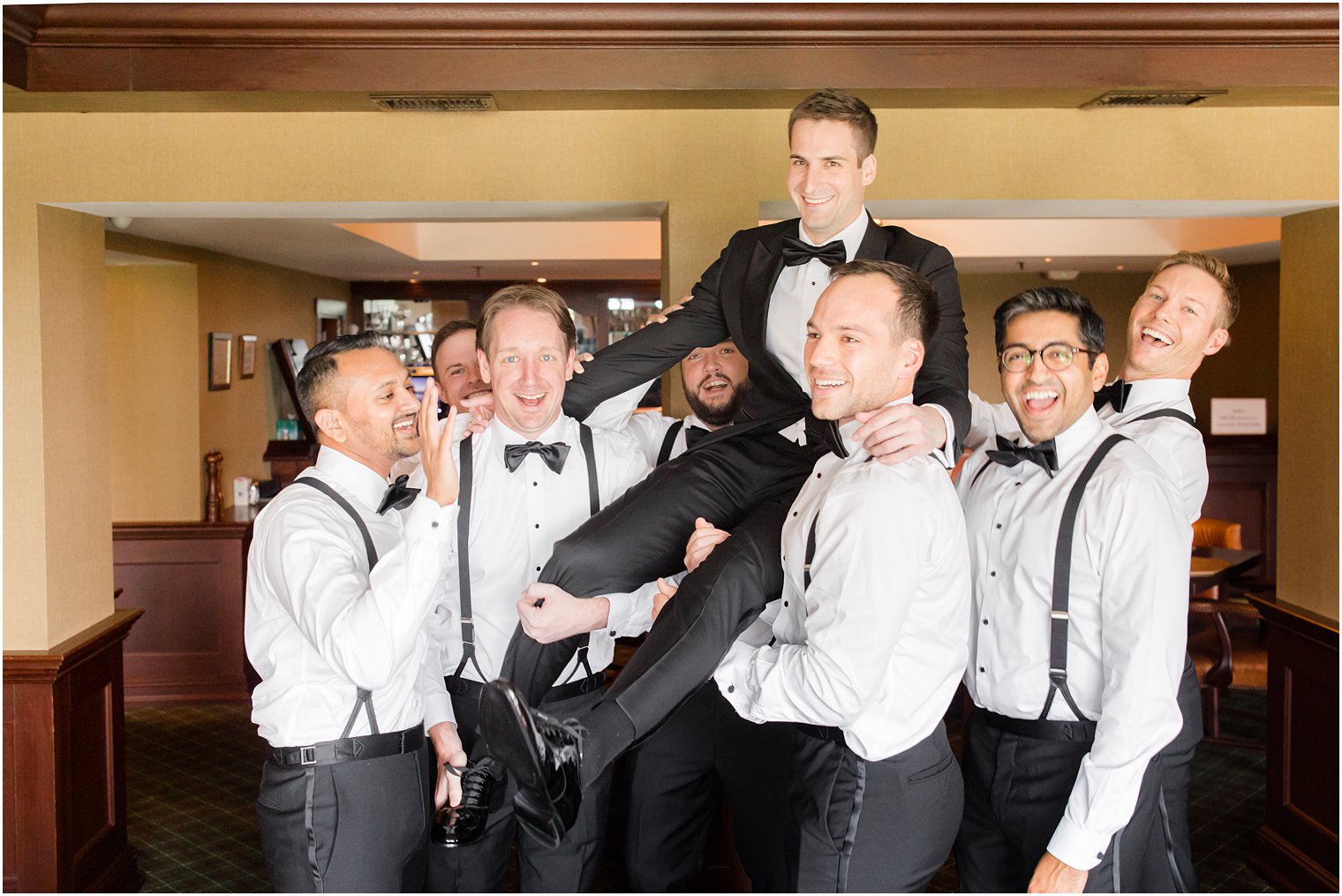 groomsmen lift groom during wedding day prep at Indian Trail Club