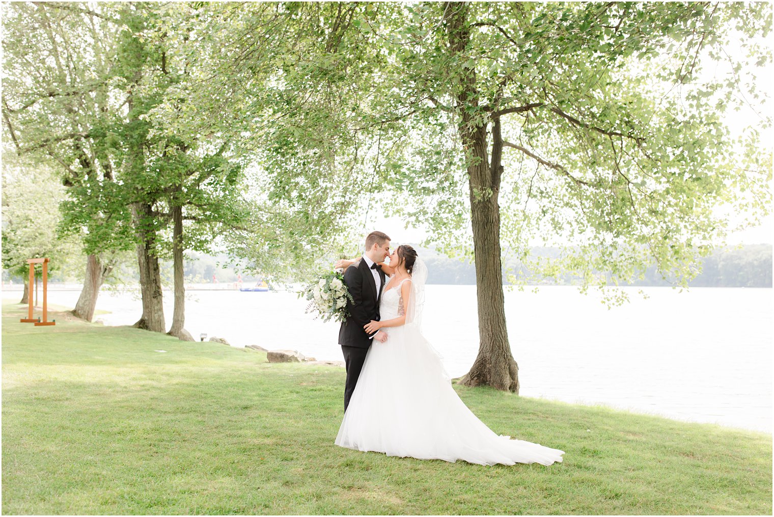 bride and groom kiss by waterfront in Franklin Lakes, NJ