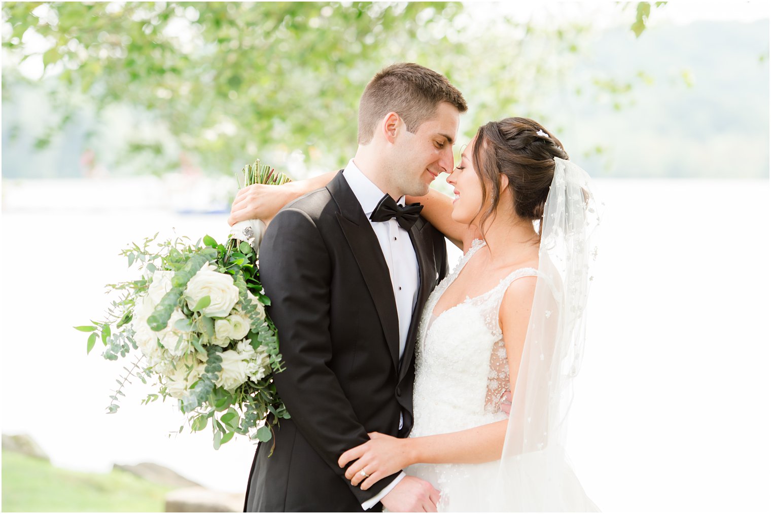 bride and groom pose along water touching noses in New Jersey 