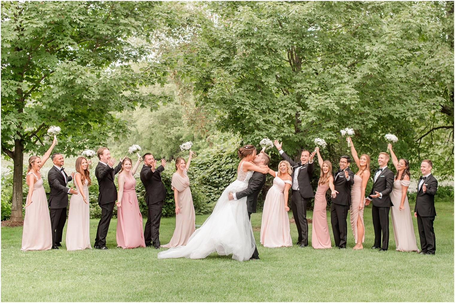 groom lifts bride during photos with wedding party at Indian Trail Club