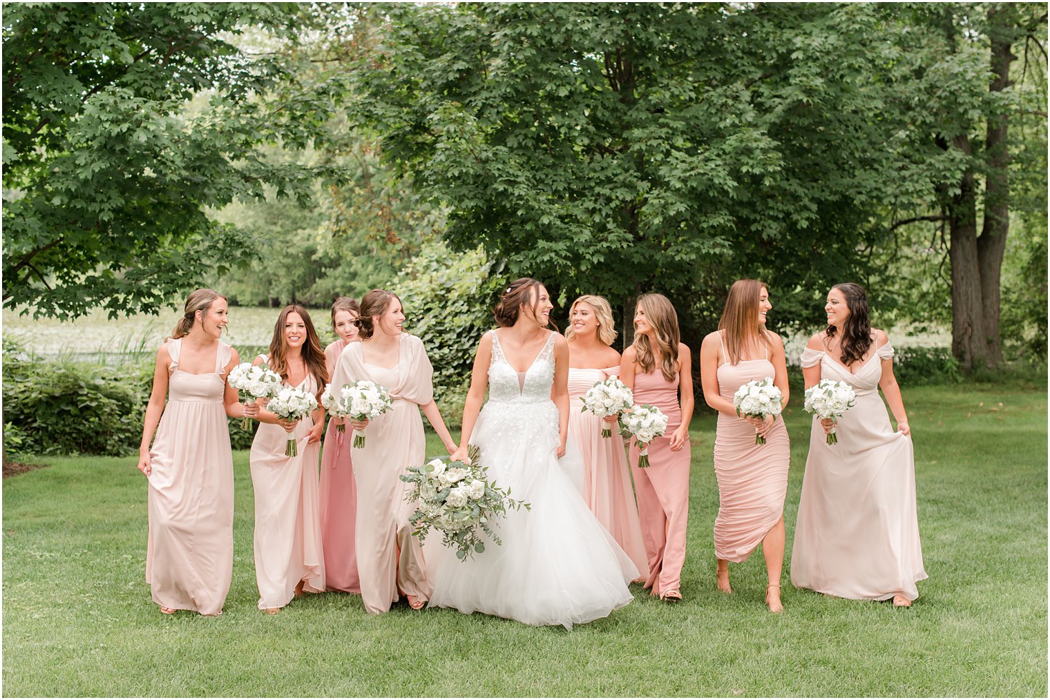 bride walks with bridesmaids in pink gowns at Indian Trail Club