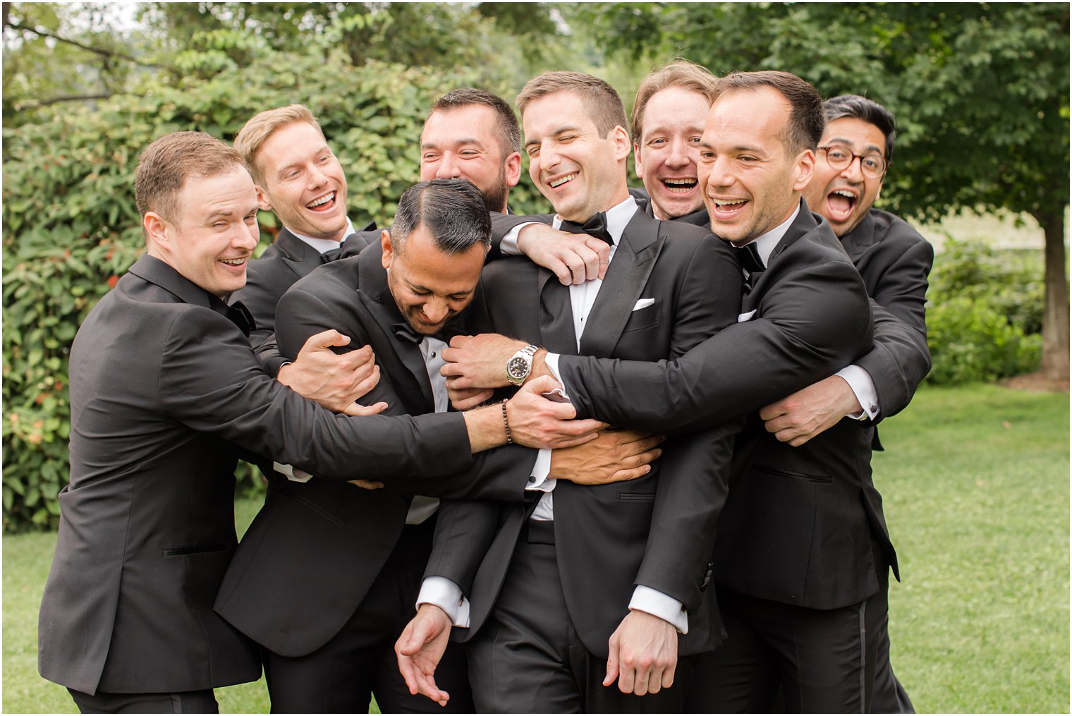 groom laughs while groomsmen hug him in Franklin Lakes NJ