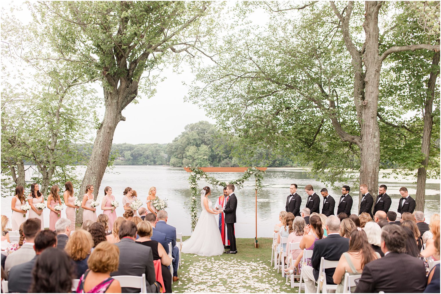 bride and groom hold hands during waterfront wedding ceremony in Franklin Lakes NJ