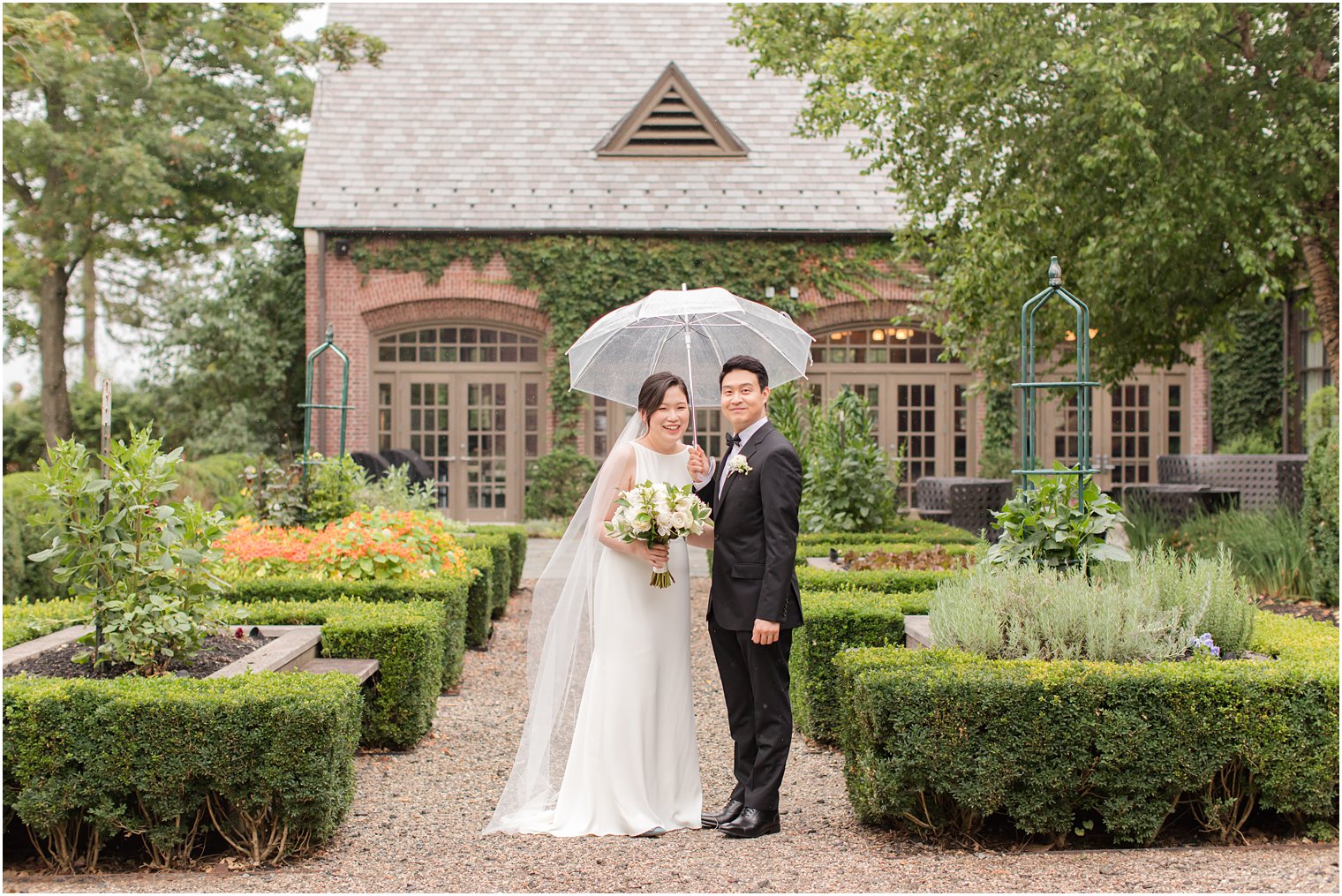 bride and groom pose under umbrella on rainy wedding day in Peapack NJ