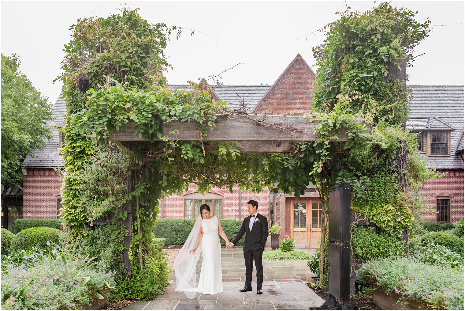 bride and groom hold hands under wooden arbor at Ninety Acres