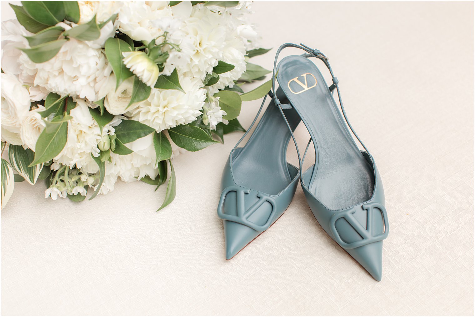 bride's blue shoes rest near white bouquet