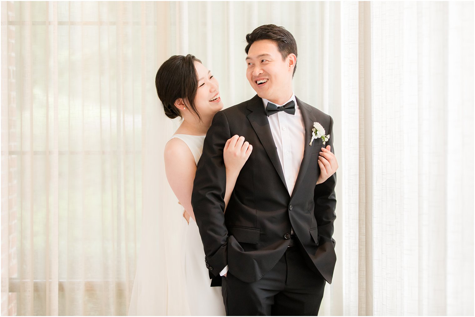 bride hugs groom from behind in classic tux