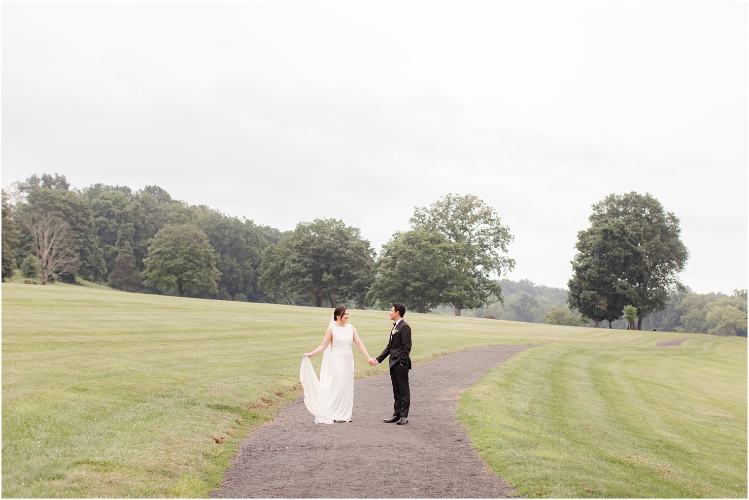 newlyweds pose on driveway during portraits at Ninety Acres