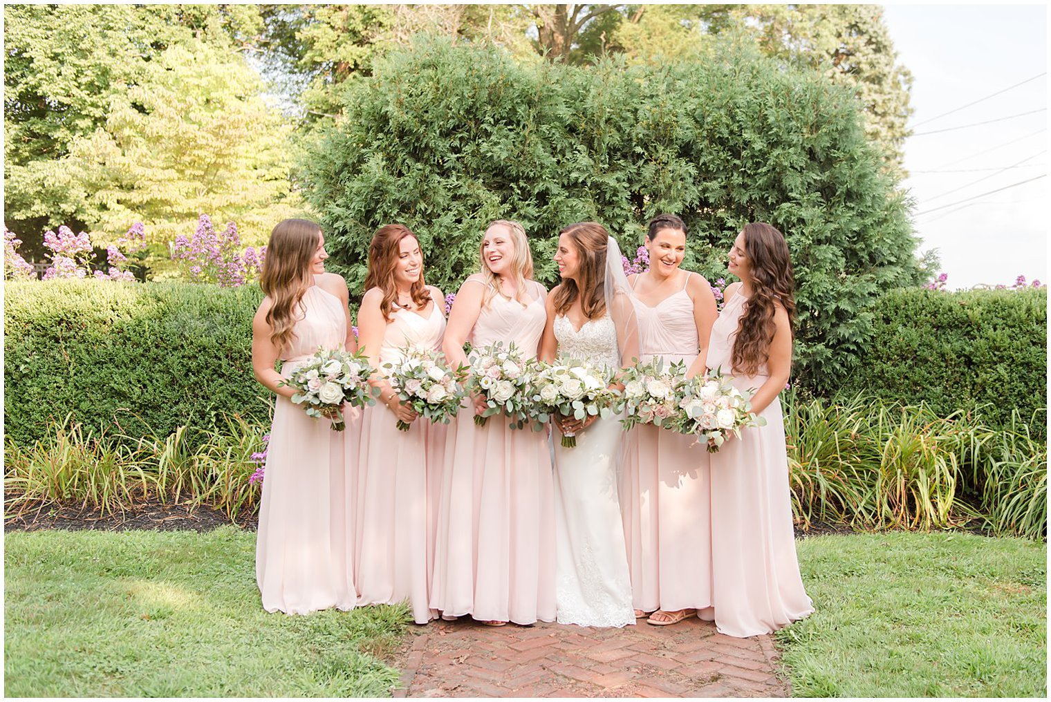bride laughs with bridesmaids in pale pink dresses