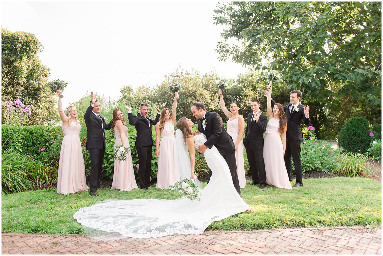 groom dips bride while wedding party cheers at the Inn at Fernbrook Farms