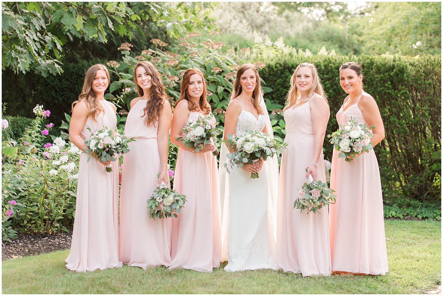bride poses with bridesmaids in pink gowns for NJ wedding