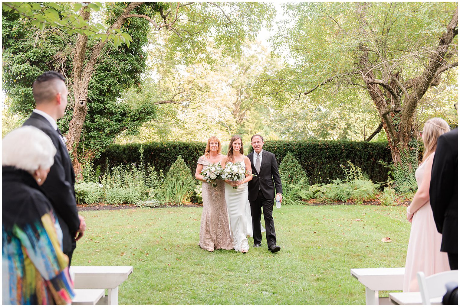 bride walks down aisle with parents for Inn at Fernbrook Farms wedding ceremony