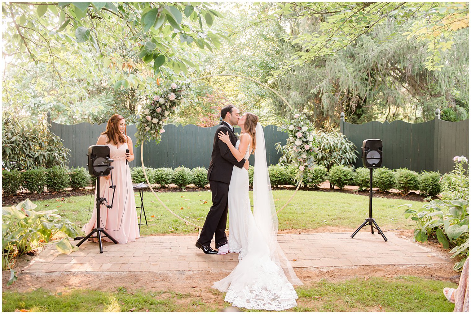 newlyweds kiss by gold circle at Inn at Fernbrook Farms