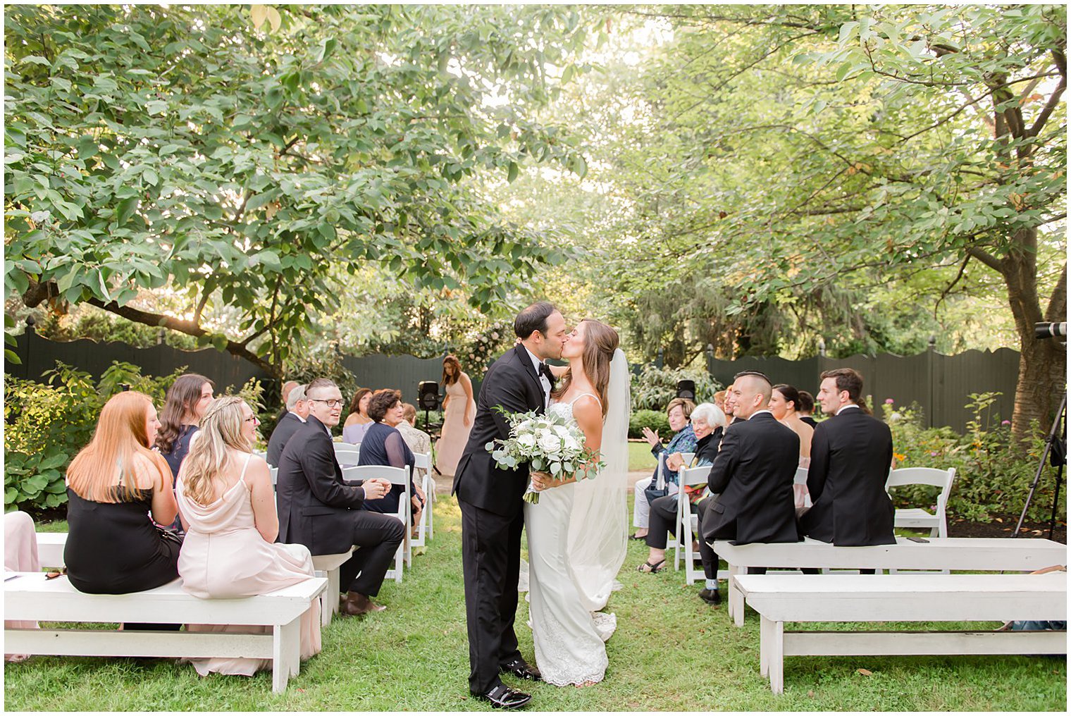 newlyweds kiss at the end of the aisle at the Inn at Fernbrook Farms