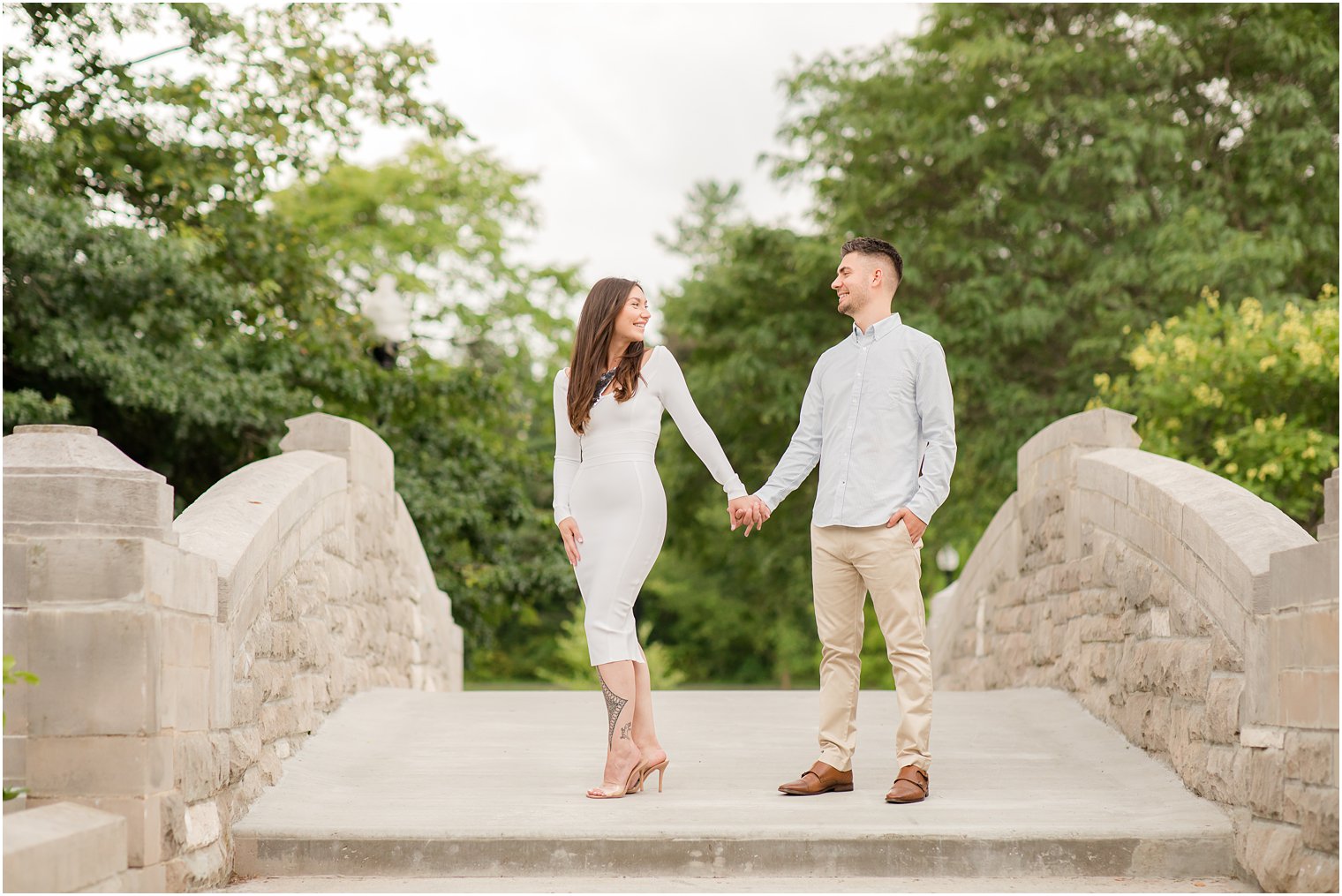 couple poses on bridge during Verona Park engagement session