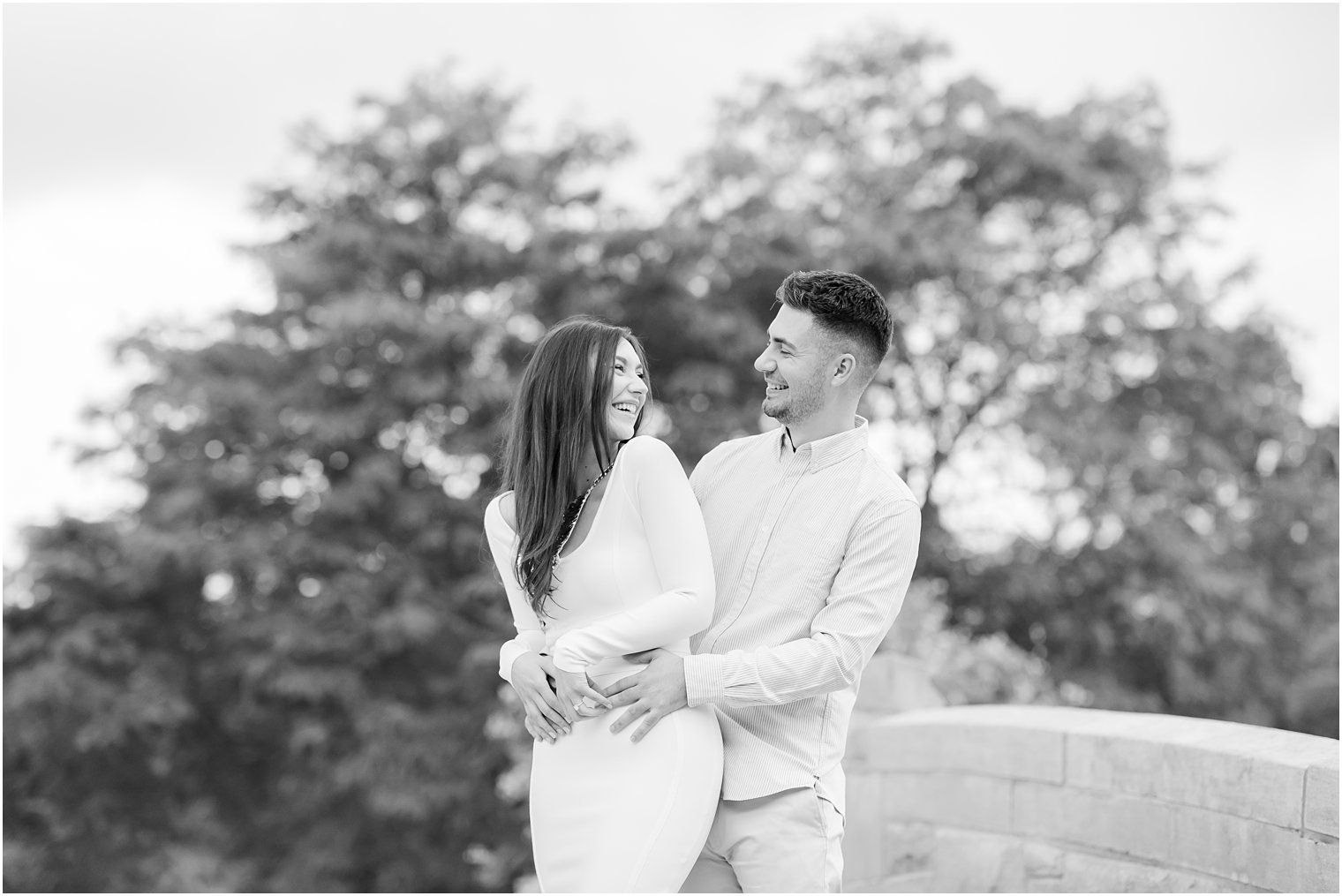 groom holds bride's hips during Verona Park engagement session on bridge