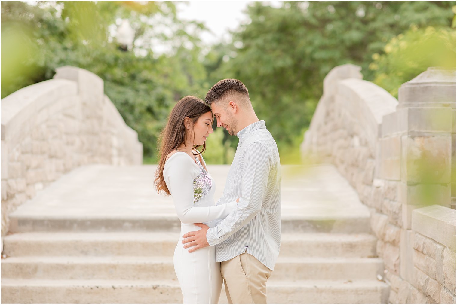 engaged couple poses on stone bridge during Verona Park engagement session