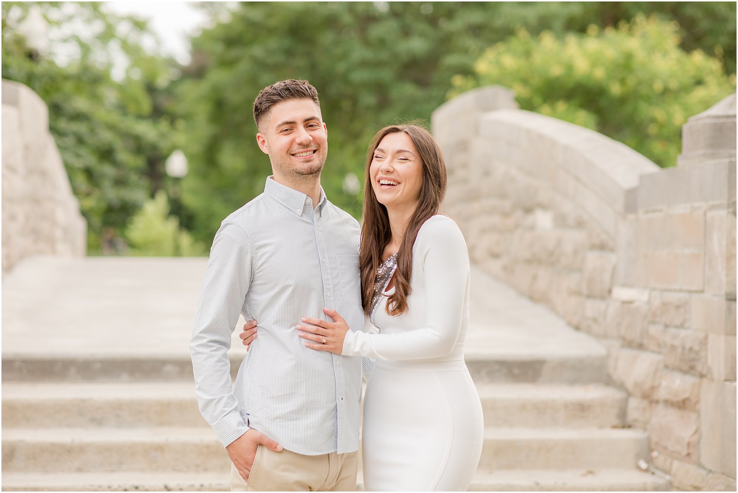 engaged couple laughs on stone bridge during Verona Park engagement session