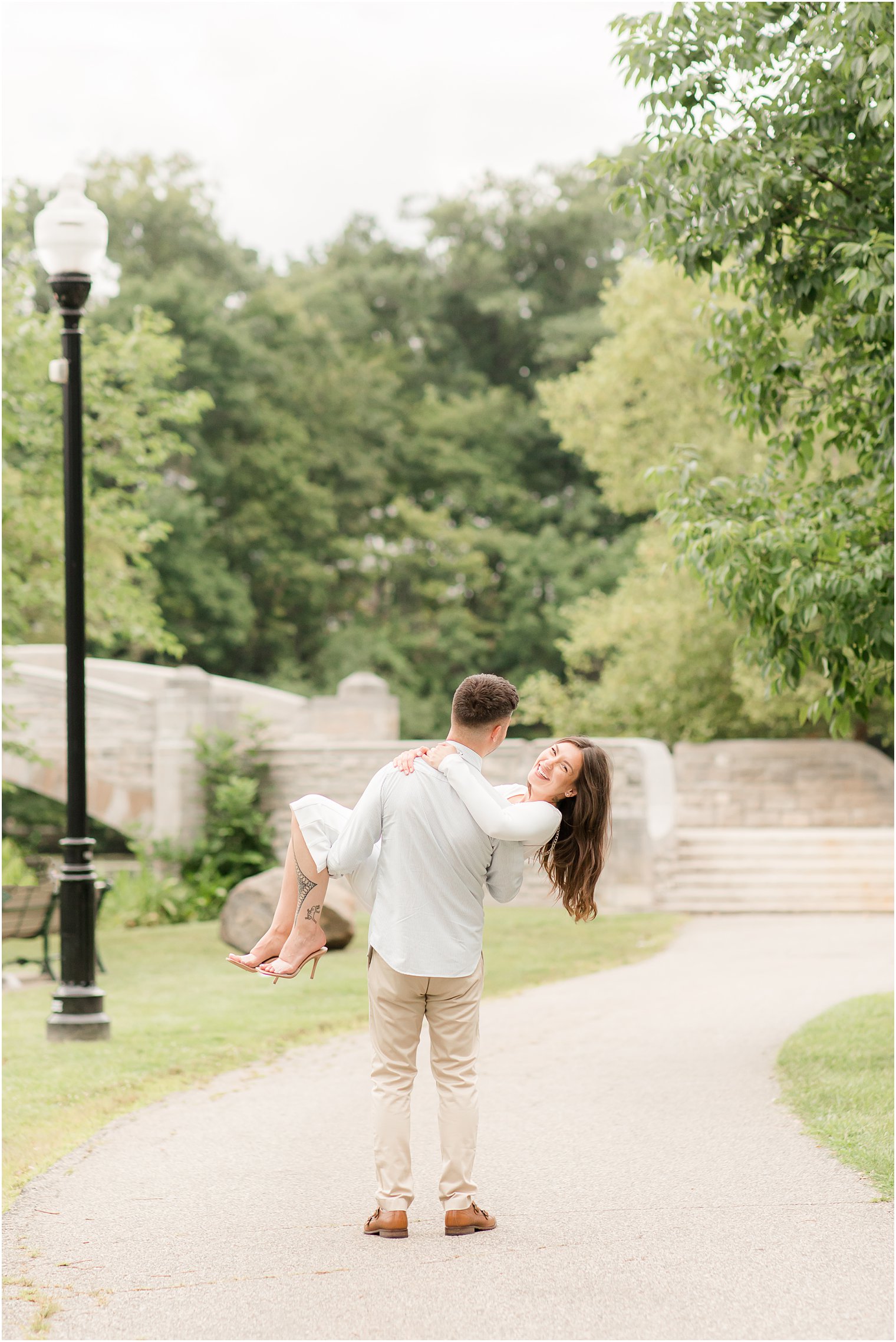 groom lifts bride during Verona Park engagement session