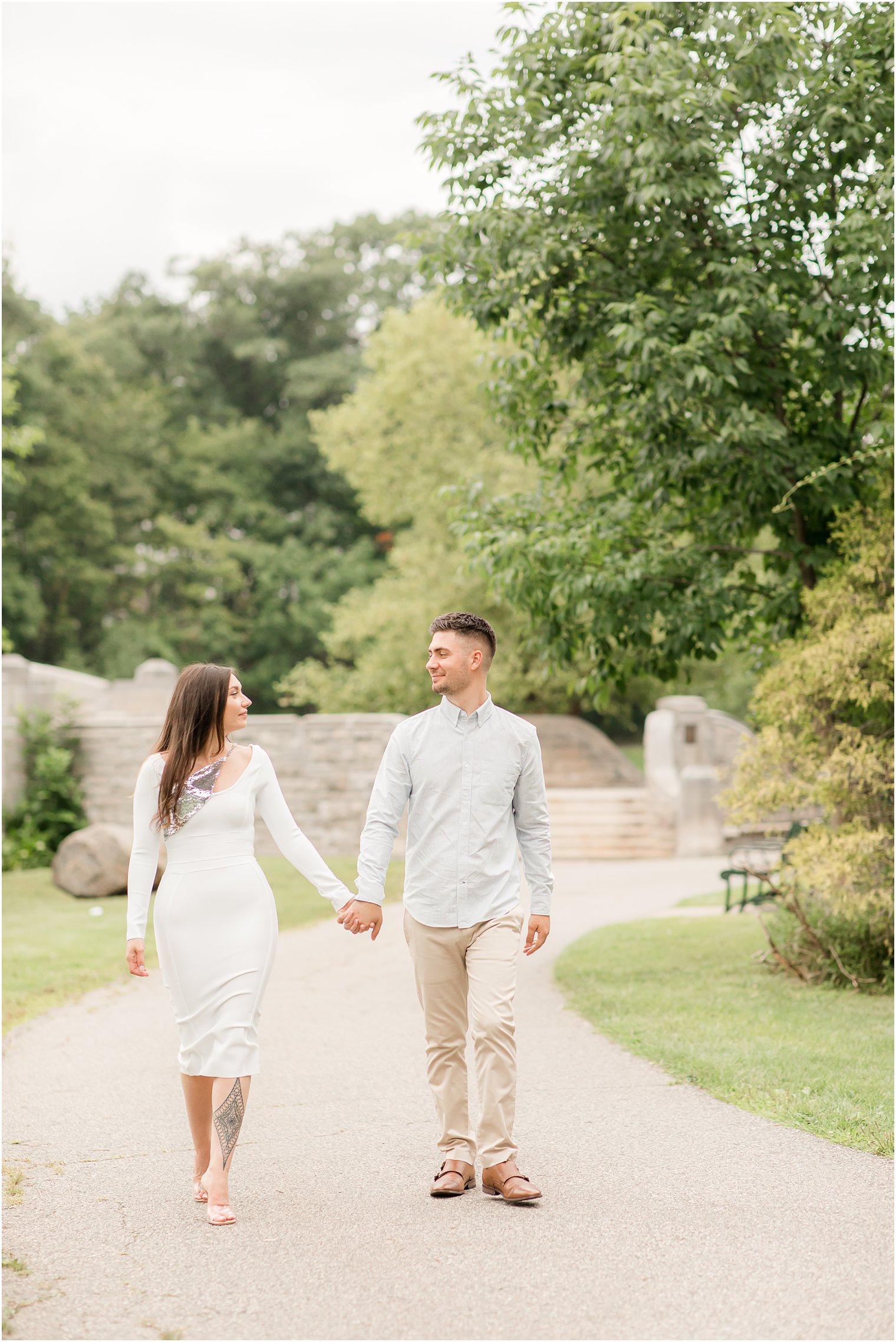 engaged couple holds hands walking through Verona Park