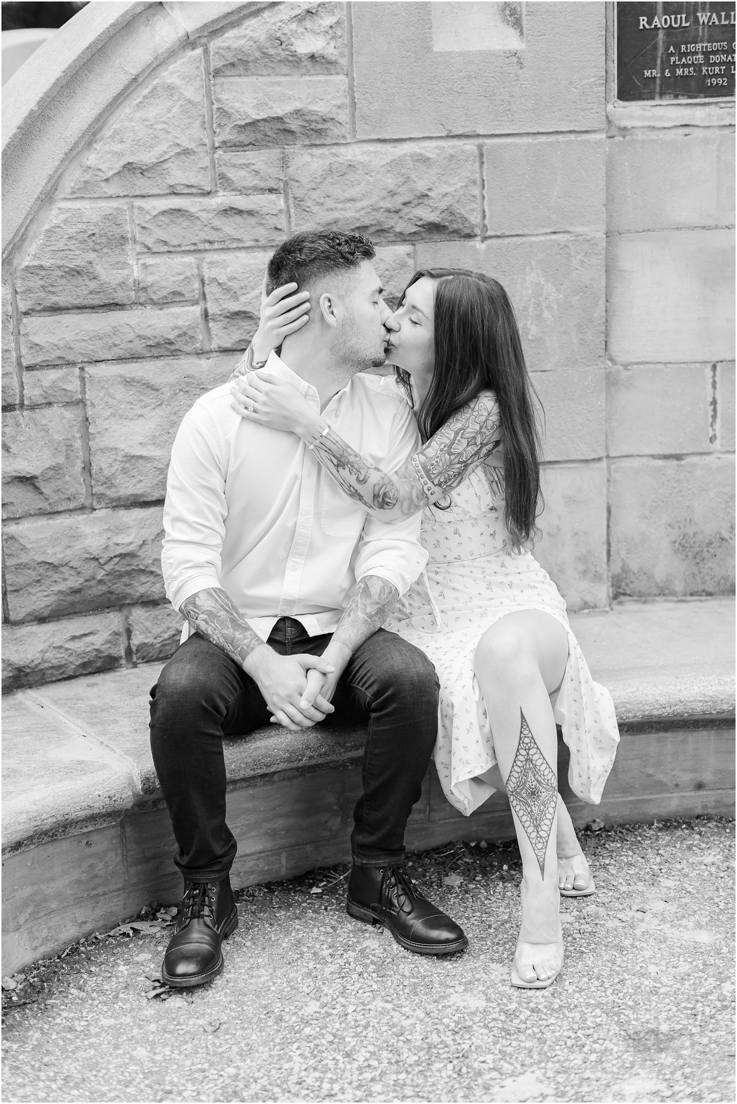 couple sits on stone bench during NJ engagement session in Verona Park