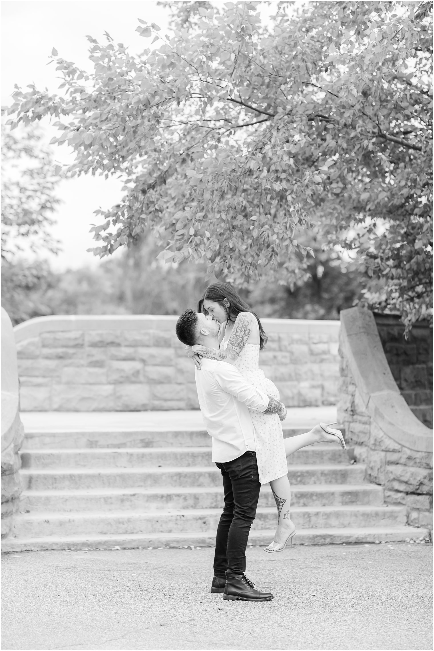 groom lifts bride up kissing her during Verona Park engagement session