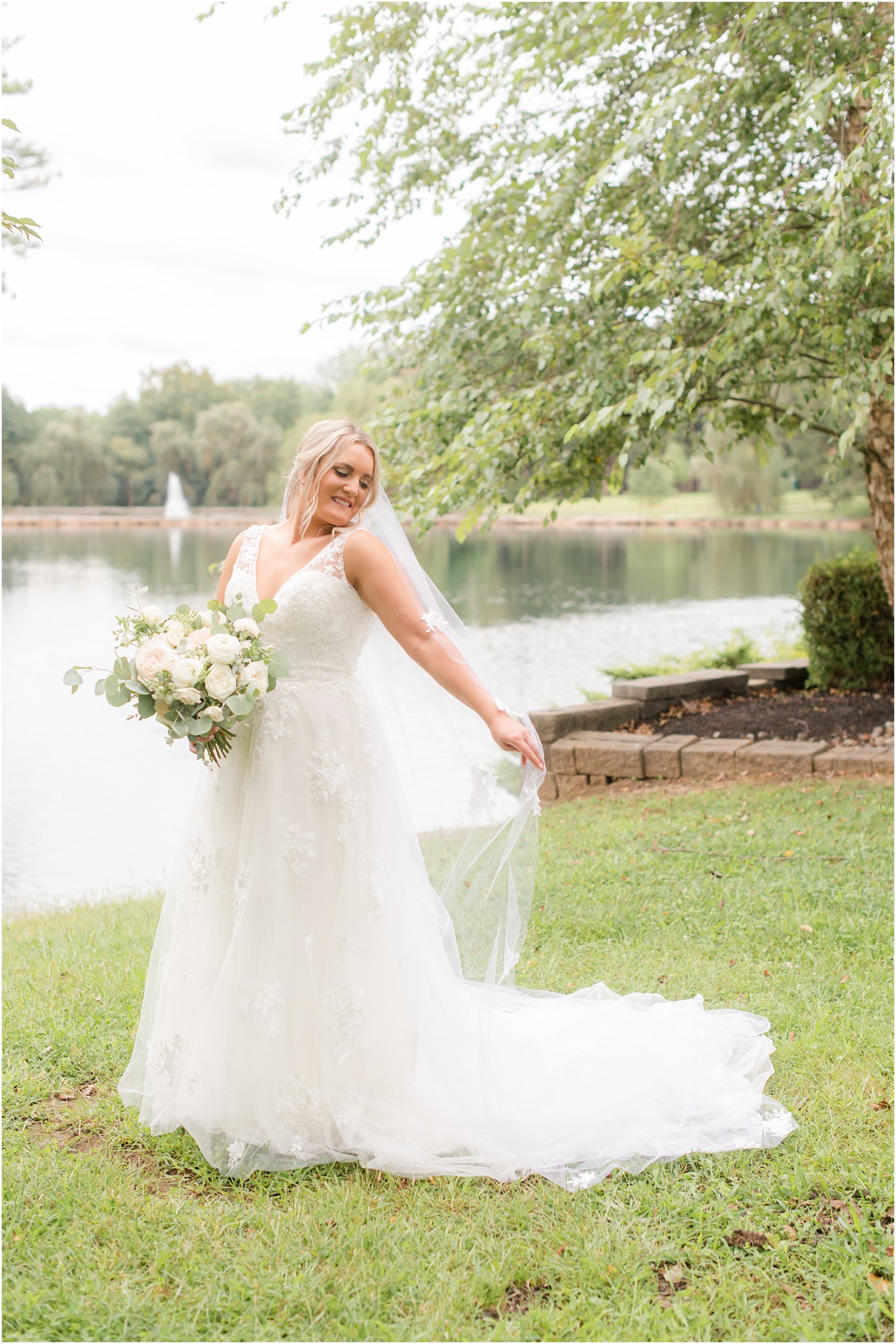 bride holds veil behind her during NJ wedding portraits 