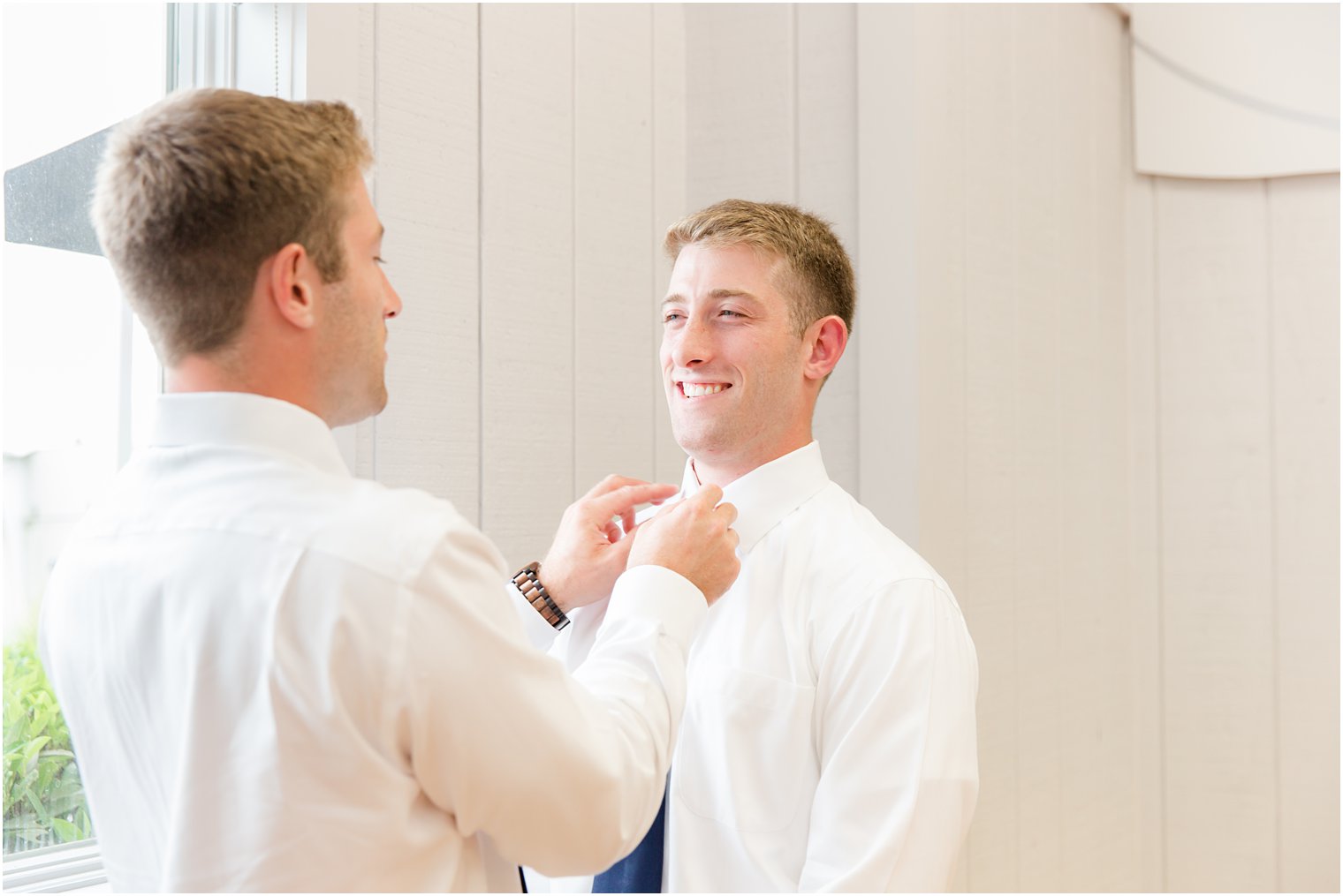 twin helps groom with tie
