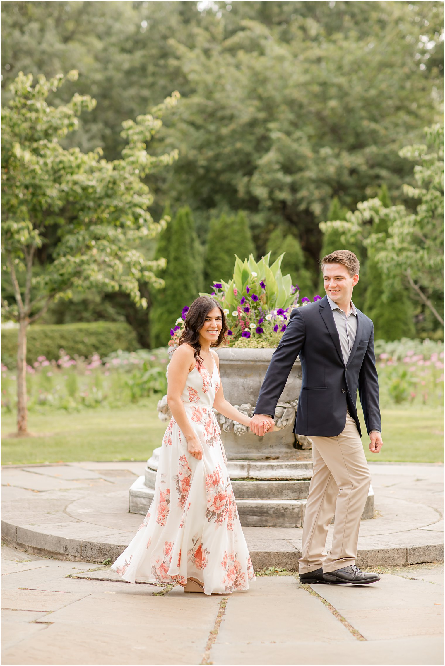 engaged couple hold hands walking around floral display in New Jersey 