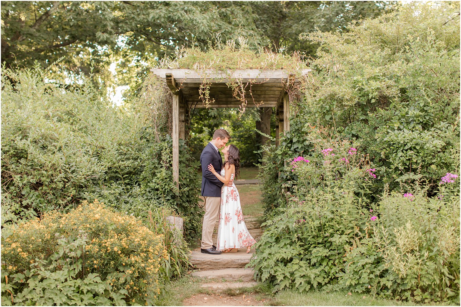 bride and groom pose by wooden arbor during Skylands Manor engagement session