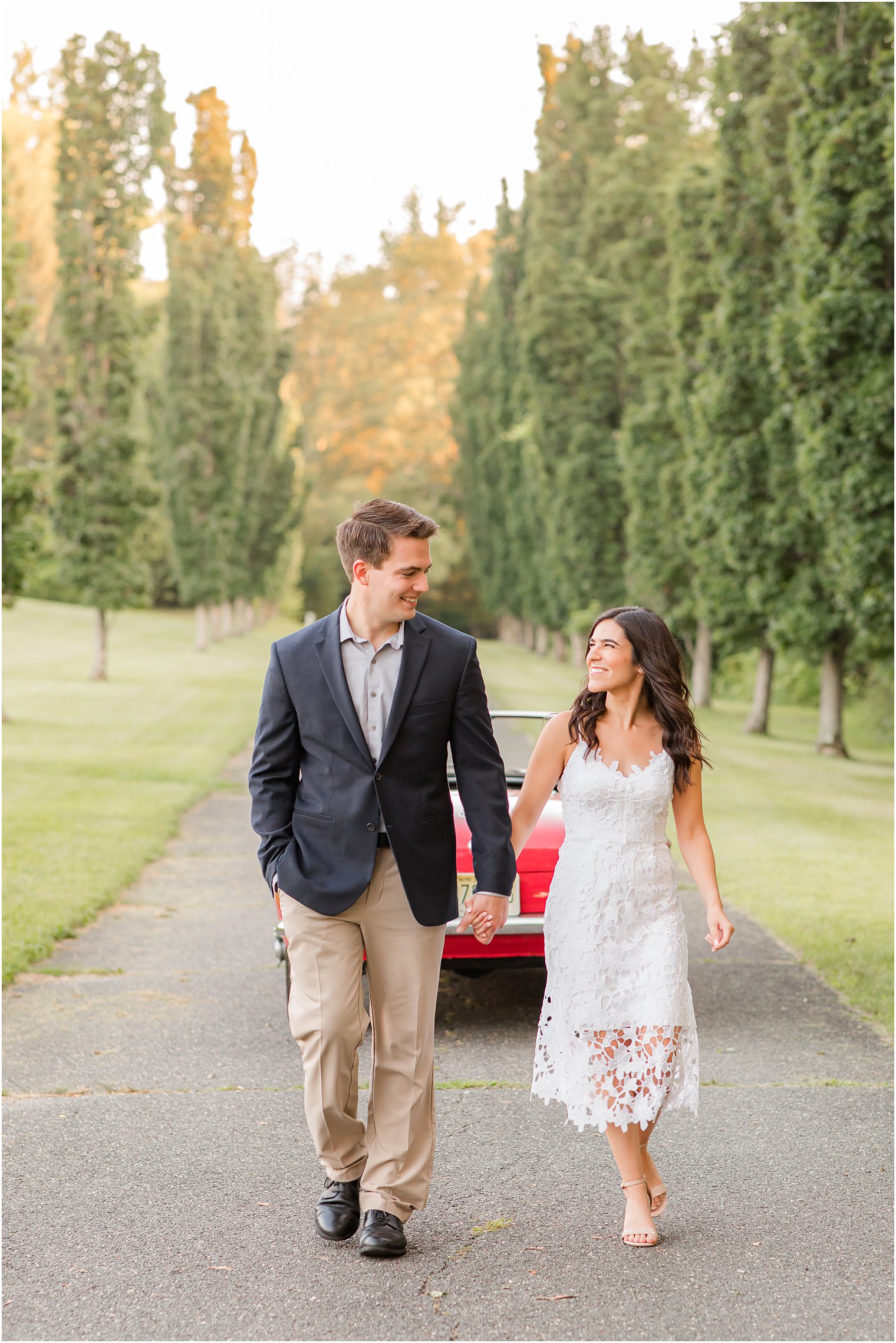 engaged couple walks with red car behind them during Skylands Manor engagement session