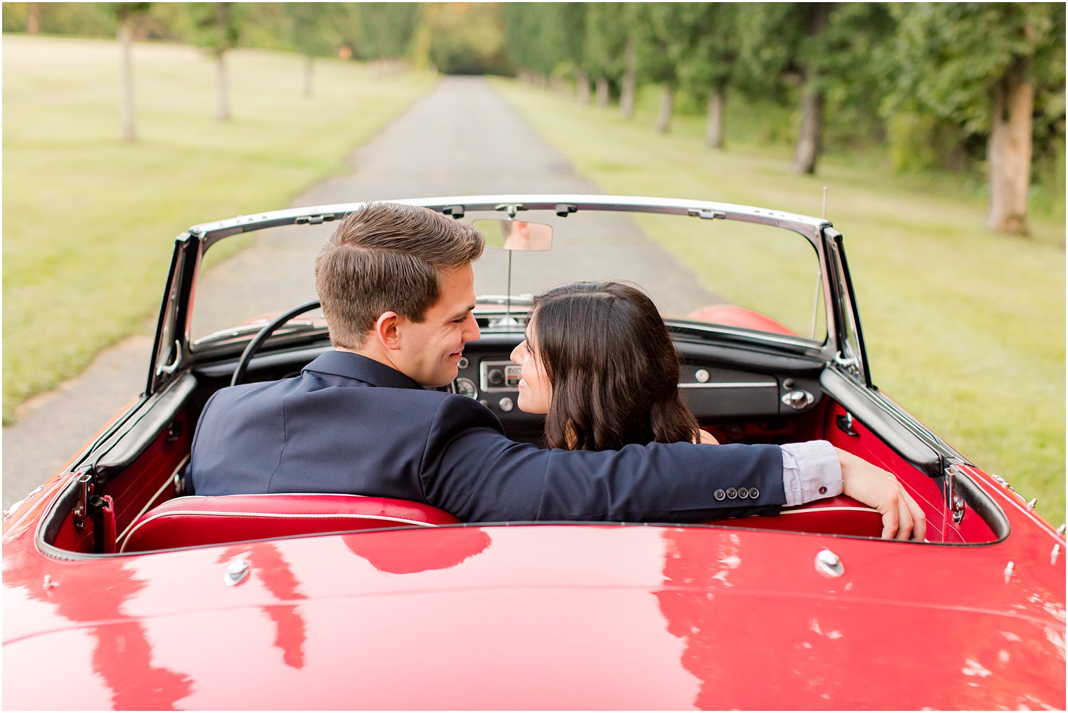 bride and groom snuggle in backseat of red car during Skylands Manor engagement session