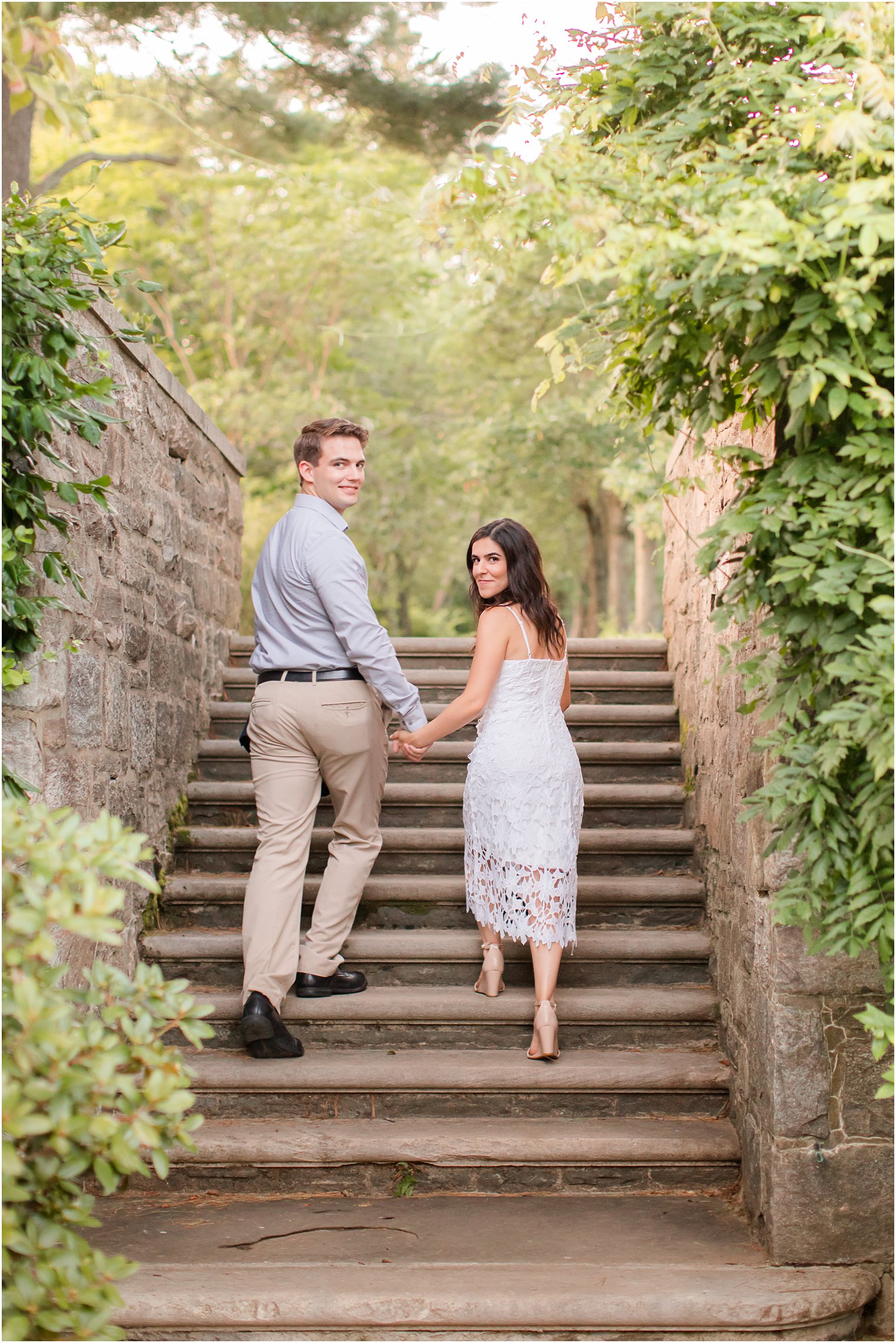 engaged couple holds hands walking up steps at Skylands Manor