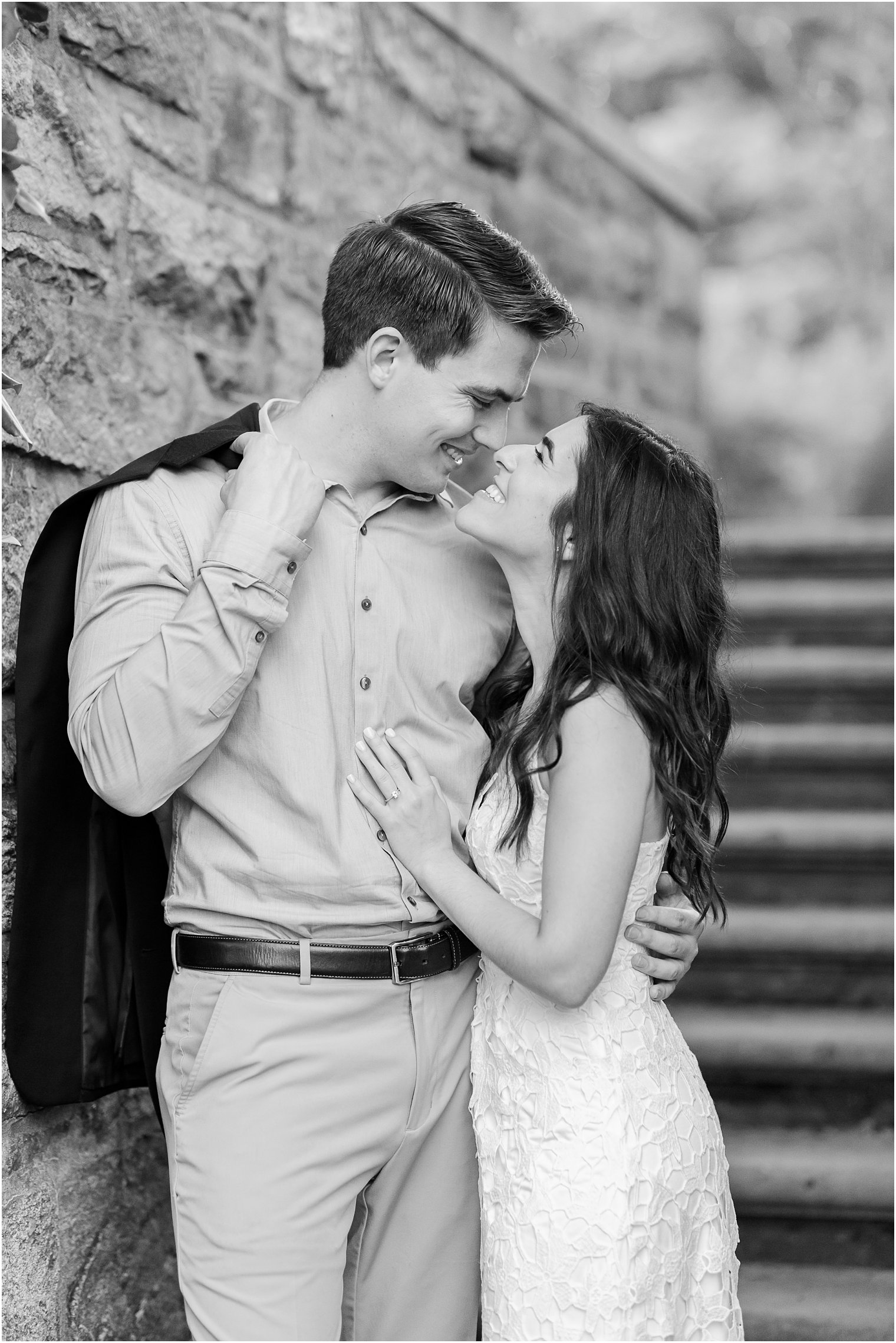 bride and groom hug along stone wall at Skylands Manor