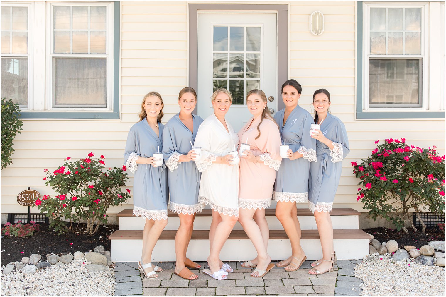 bride poses with bridesmaids in matching robes and holding matching cups before Brant Beach Yacht Club Wedding