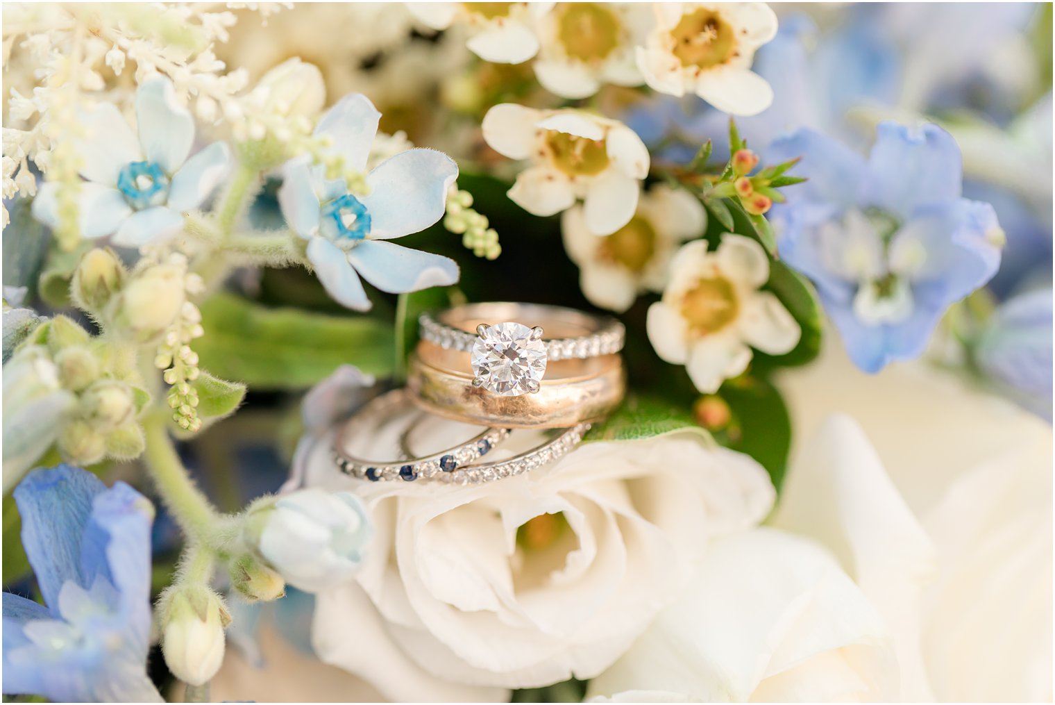 wedding rings rest on blue and white flowers 