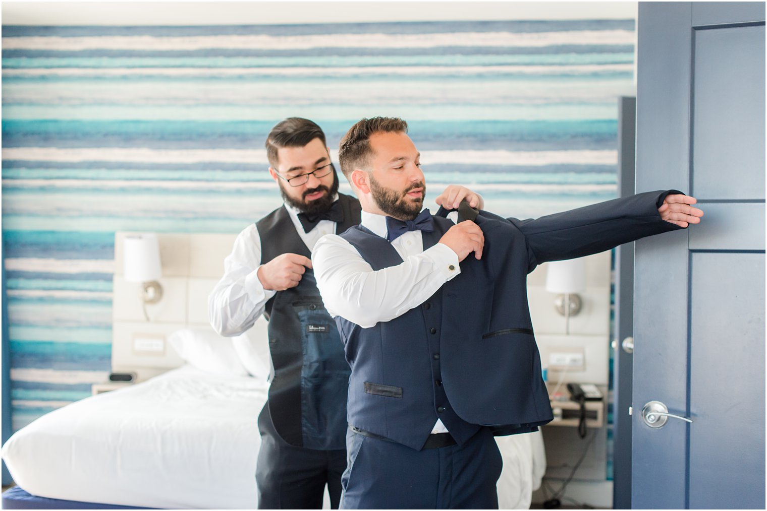 groomsmen helps groom into coat at Brant Beach Yacht Club