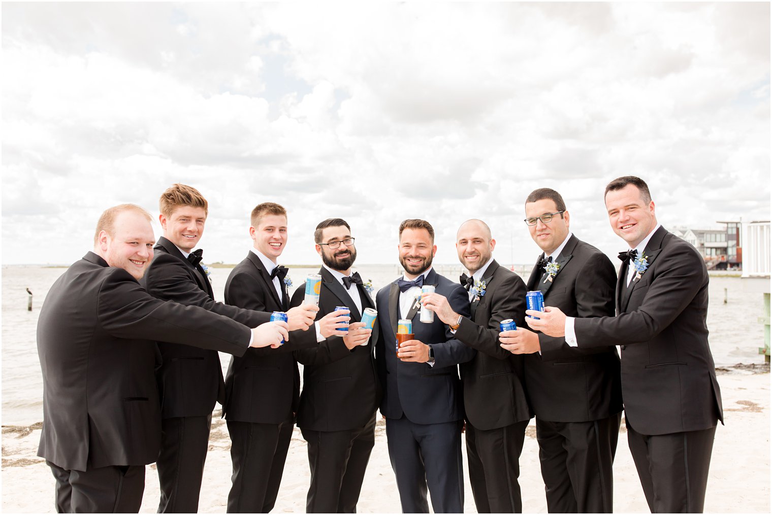 groom and groomsmen toast during portraits on the beach 