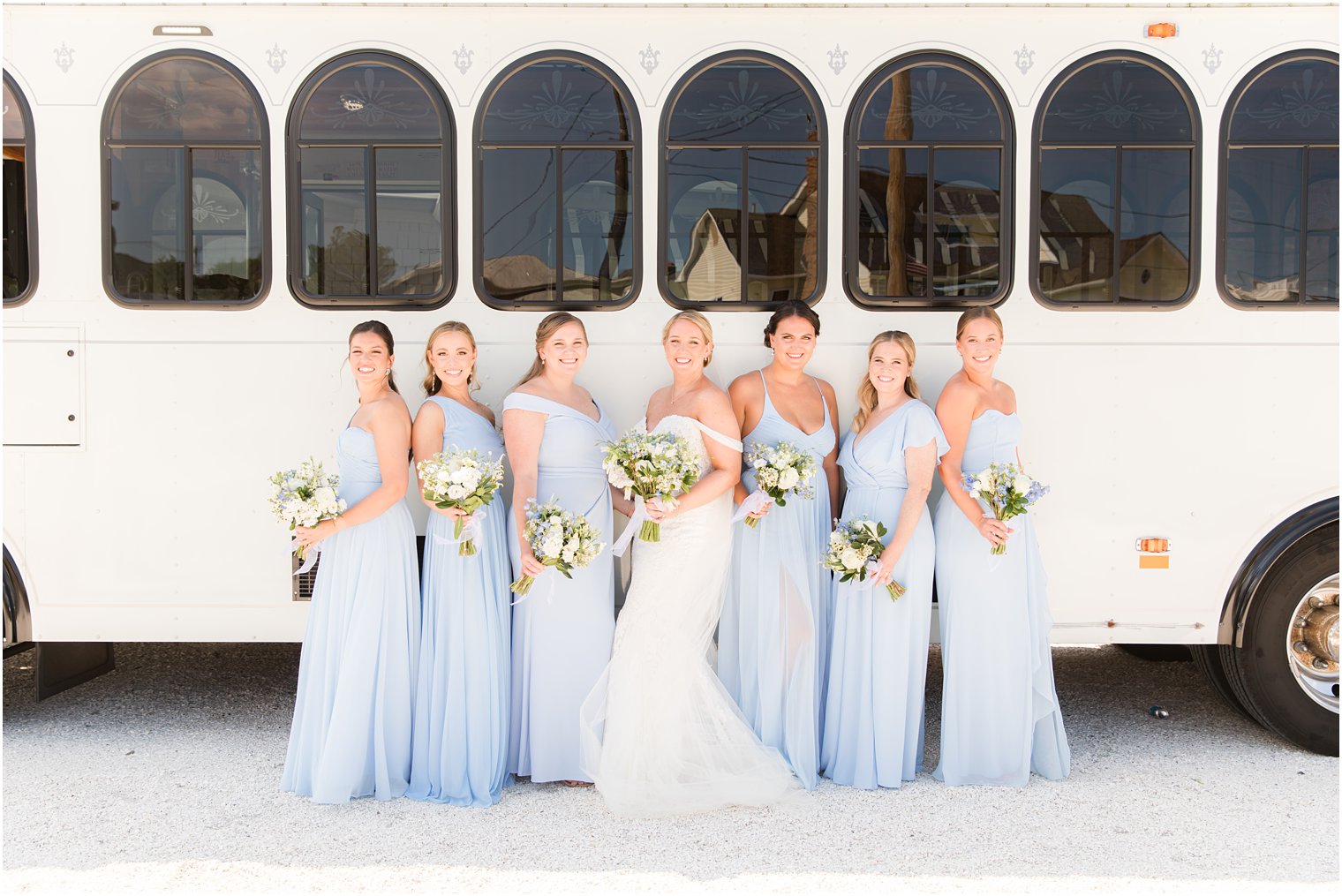bride poses with bridesmaids in light blue gowns by trolley
