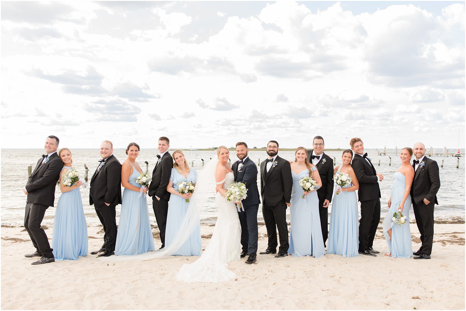 bride and groom pose with wedding party in black and blue 