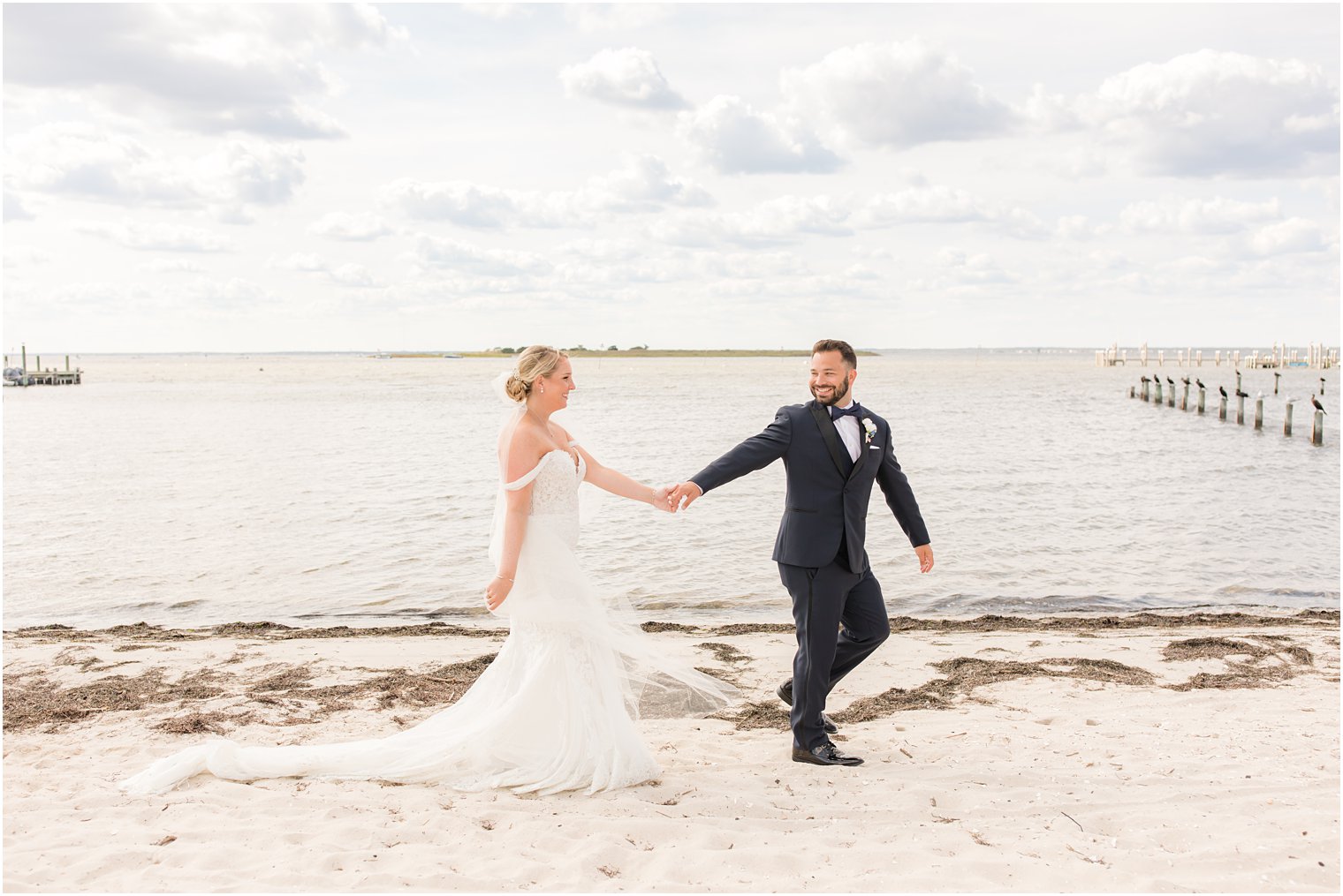 groom walks with bride on sand during NJ wedding portraits 