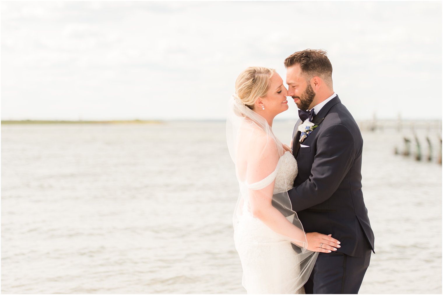 bride and groom pose together on beachfront