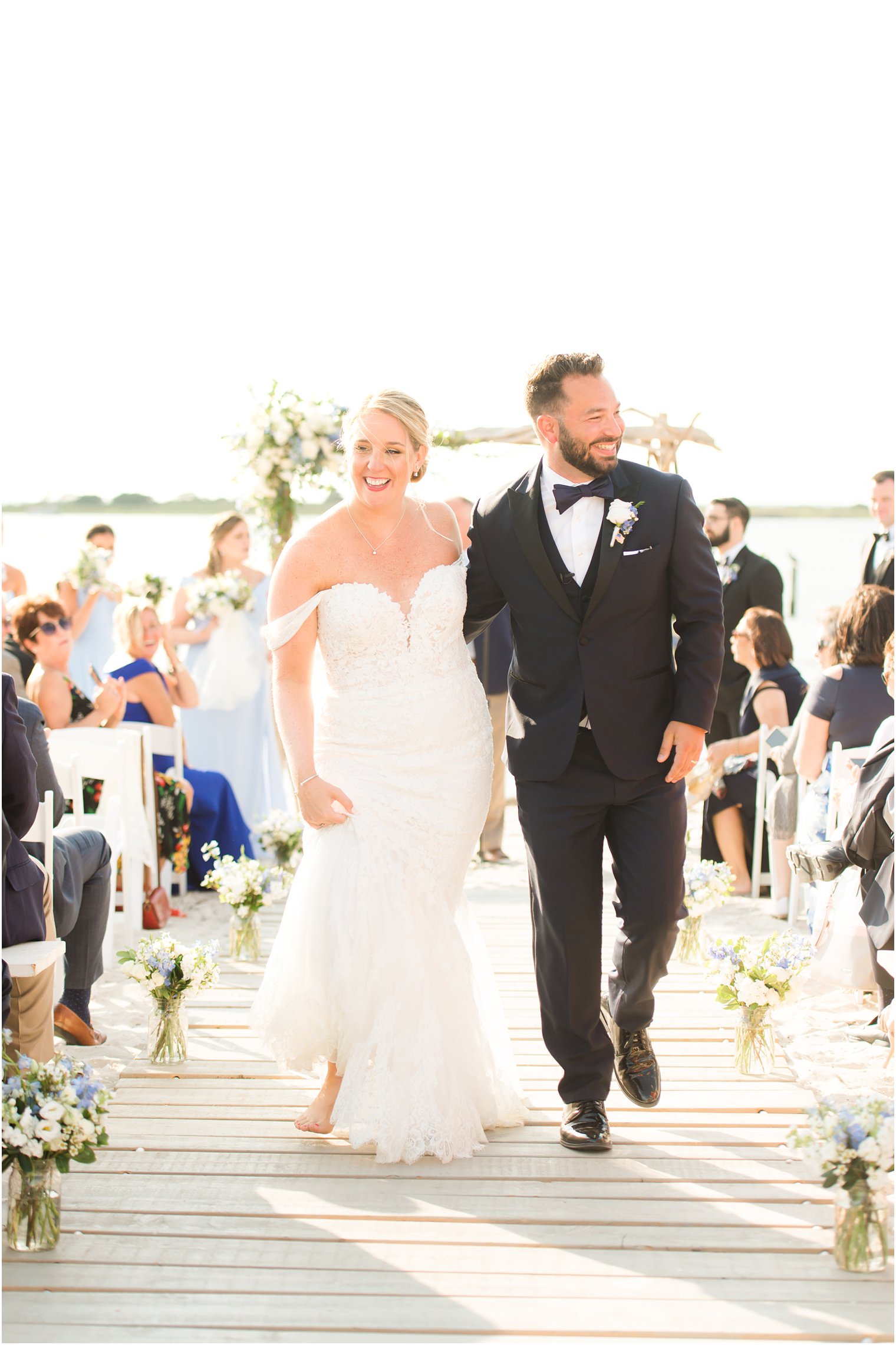 newlyweds smile walking up the aisle together after waterfront beach ceremony