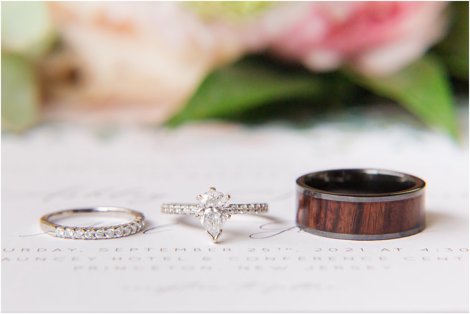 bride and groom's rings rest on wedding invitation 