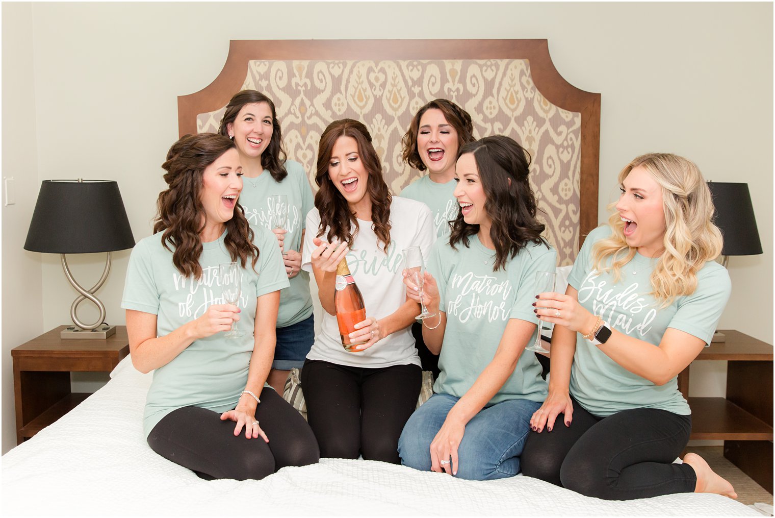 bride pops pink champagne with bridesmaids during fall wedding day prep 