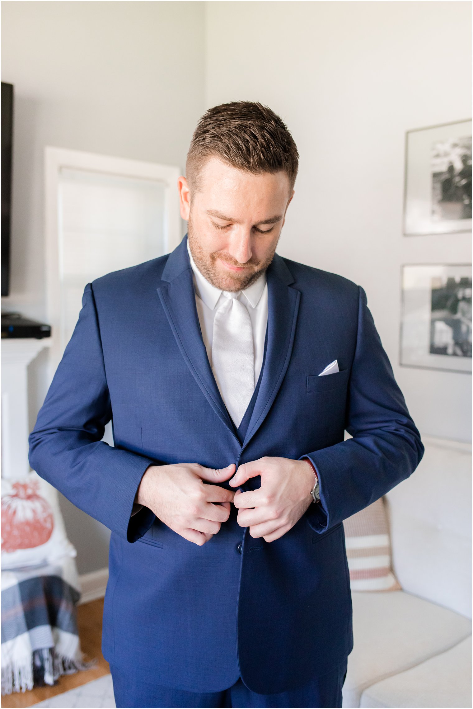 groom adjusts buttons on suit jacket before NJ wedding day 