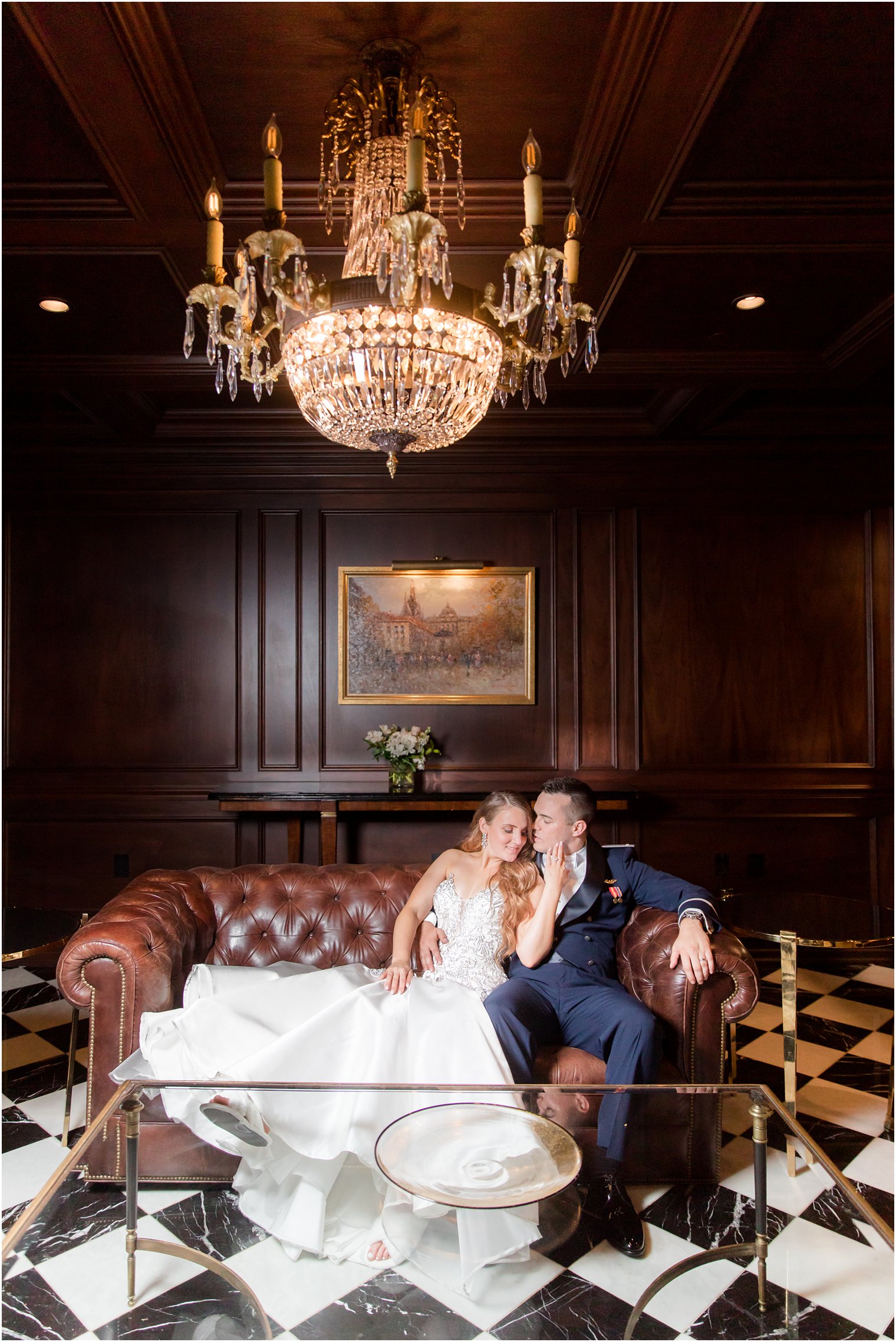 bride and groom sit on leather couch in drawing room