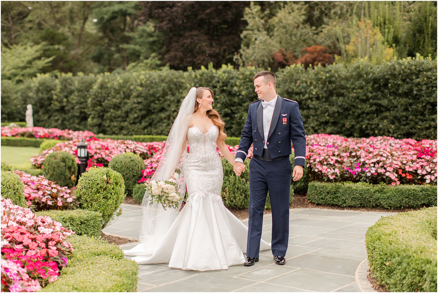 newlyweds hold hands walking through gardens of Park Chateau Estate