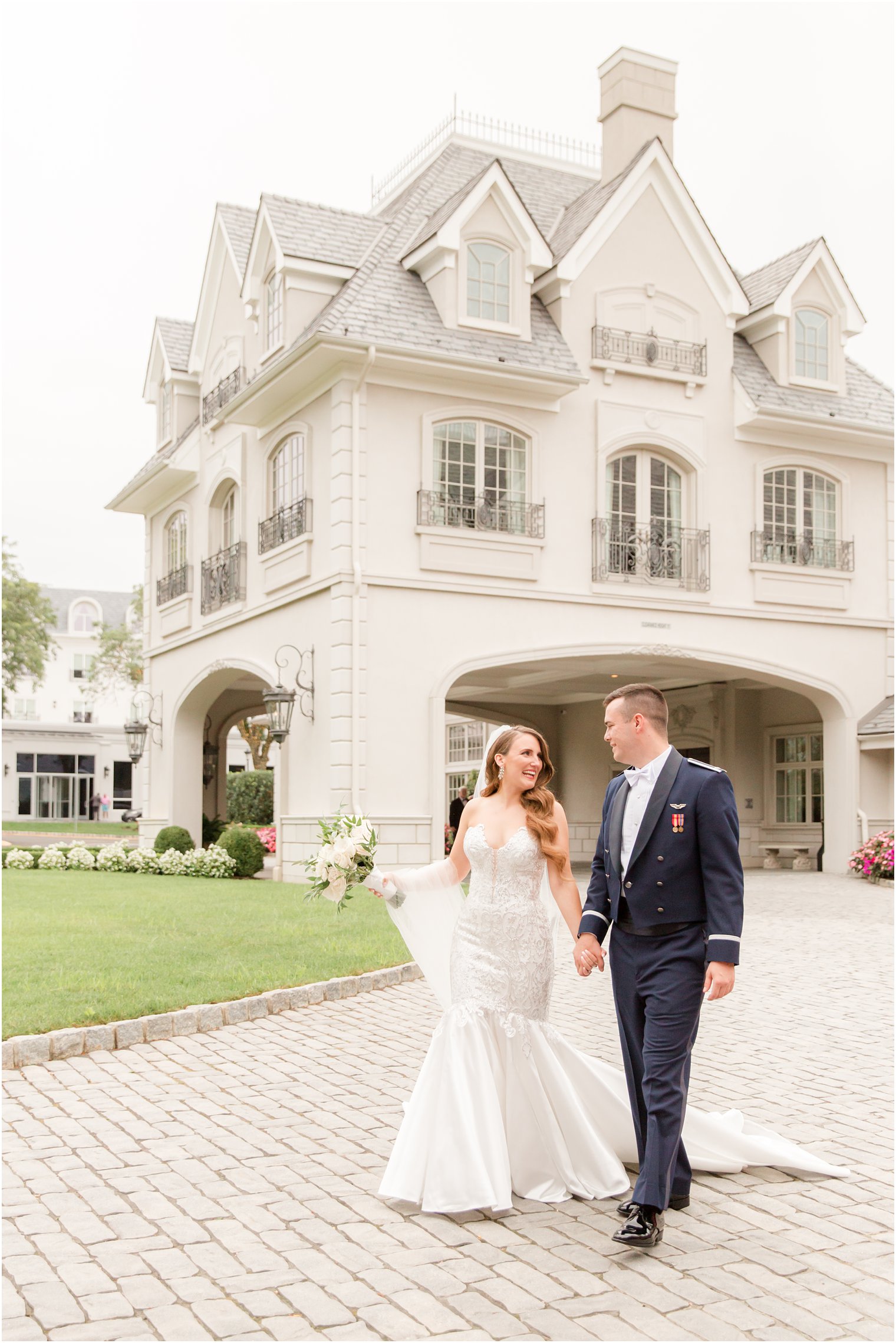 newlyweds hold hands walking on driveway at Park Chateau Estate